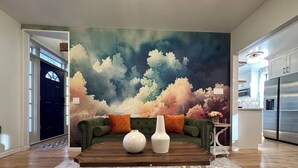A living room with a green sofa, a wooden coffee table, and a large abstract painting on the wall. - Luxury Private Boutique Hotel with CityView, Hot Tub, Free Parking (Pittsburgh)