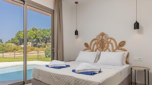A bedroom with a large bed, a view of a swimming pool, and a balcony. - Villa Ismini Periyali (Zakynthos)
