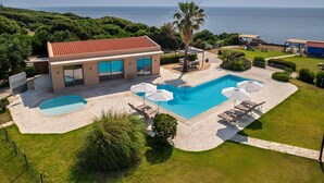 A modern villa with a swimming pool, a patio area, and a view of the sea. - Villa Ismini Periyali (Zakynthos)