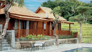 Eine Holzvilla mit Ziegeldach, Swimmingpool und einer Terrasse mit Bänken.