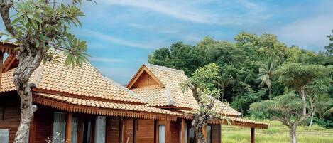 Une villa en bois avec un toit en tuiles, une piscine et un patio équipé de bancs.