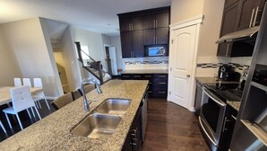 A modern kitchen with granite countertops, stainless steel appliances, and dark cabinetry. - Sean Comfy Home Modern Escape in Edmonton – Near Northgate  (Edmonton)