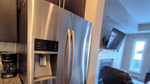 A modern kitchen with a stainless steel refrigerator, a built-in water dispenser, and a coffee maker on the counter. - Sean Comfy Home Modern Escape in Edmonton – Near Northgate  (Edmonton)