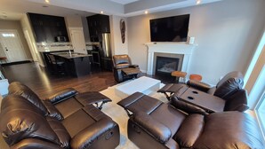 A modern living room with a sectional sofa, a fireplace, and a kitchen in the background. - Sean Comfy Home Modern Escape in Edmonton – Near Northgate  (Edmonton)