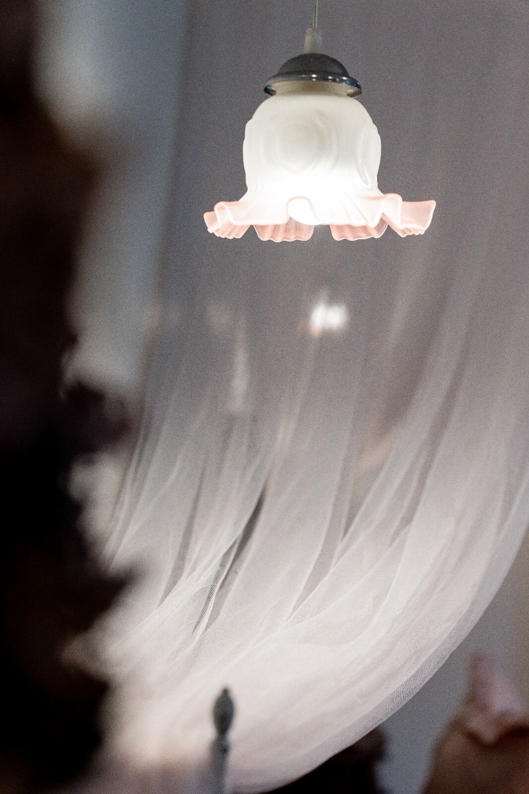 A hanging light fixture with a white shade and a ruffled edge.