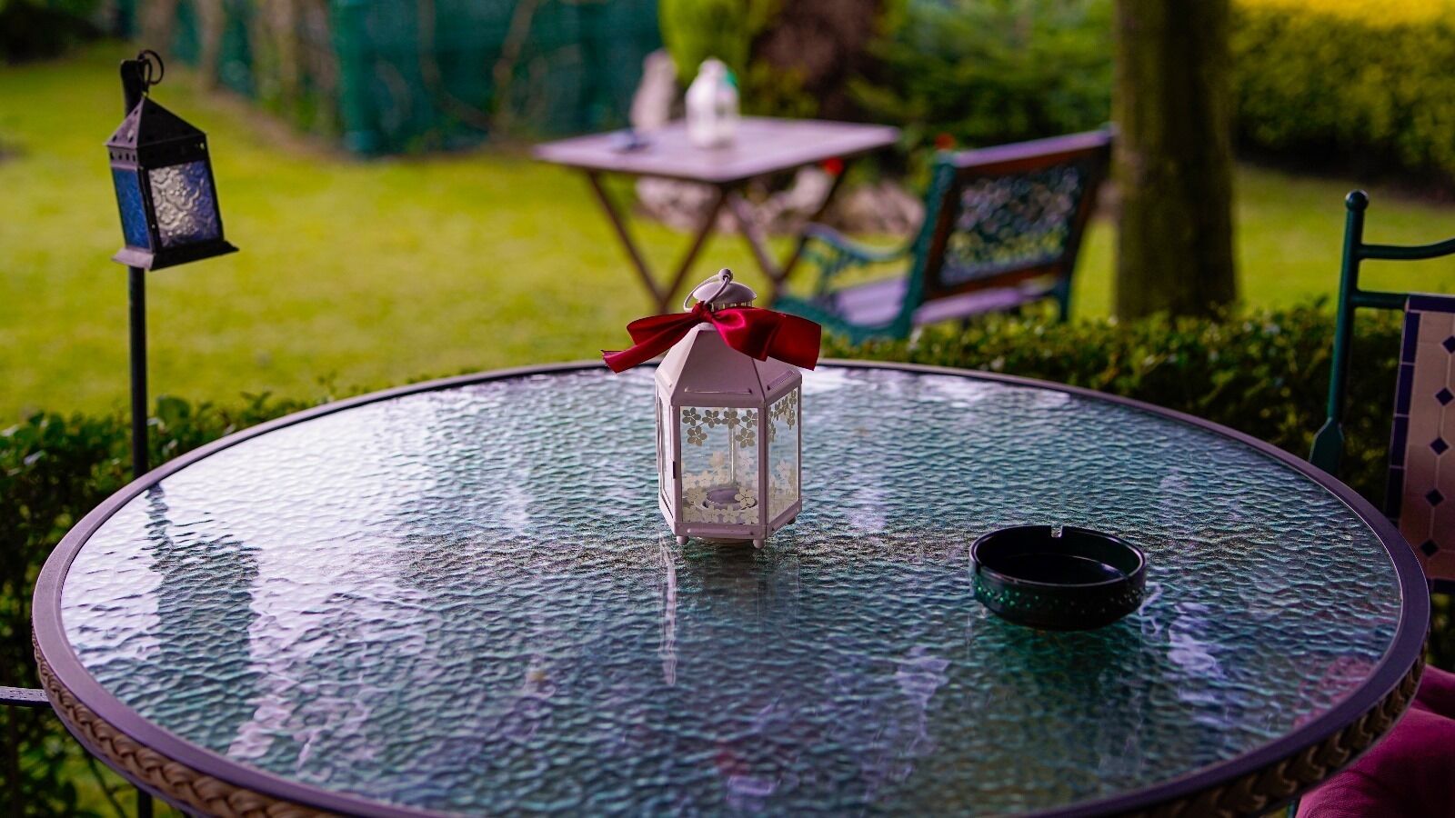 A round glass table with a lantern and a candle holder.