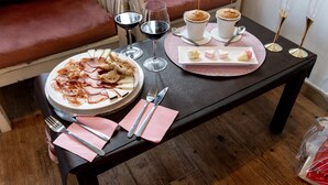 Una mesa de comedor servida con platos de comida, copas de vino y un plato decorativo con detalles en forma de corazón.