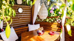 Un conjunto de banco y mesa de madera en un jardín, con un farol decorativo y un cuenco lleno de flores.