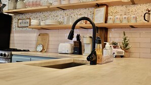A kitchen with wooden shelves, a sink, and various kitchen items.