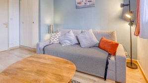 Ein gemütliches Wohnzimmer mit einer Couch, einem Couchtisch und einem Bild an der Wand.