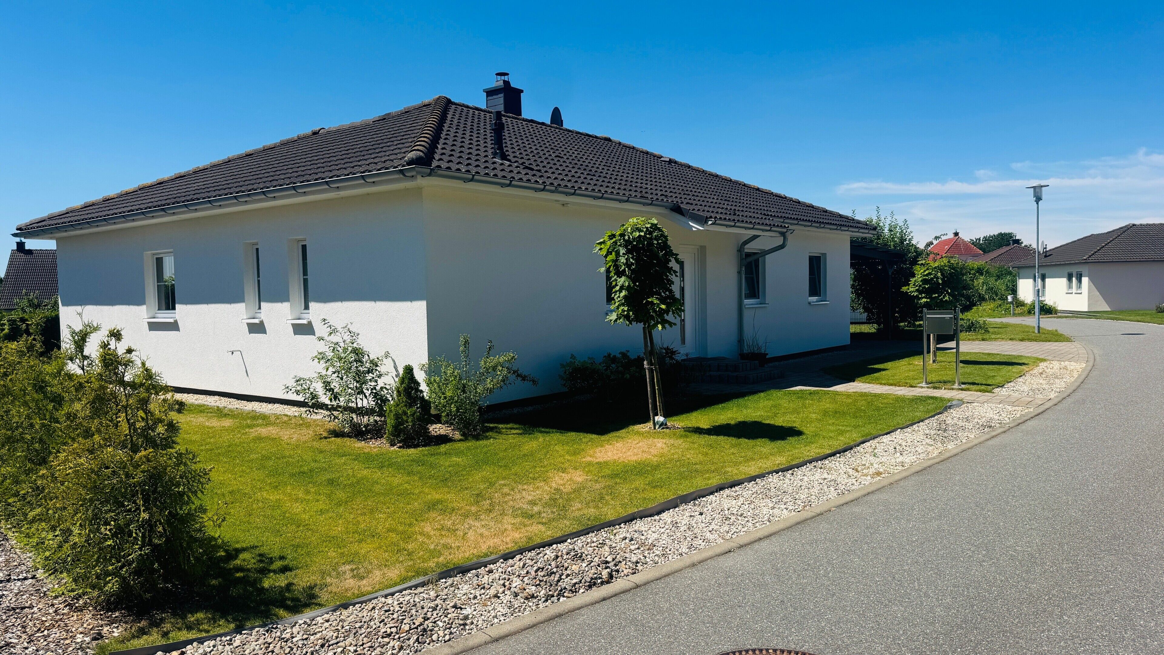 Eenlaags huis met een pannendak, een kleine voortuin met een boom en een grindpad.