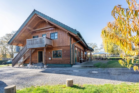A wooden log cabin with a balcony, a staircase, and a covered outdoor seating area.. Apartment 'Blockhaus' with Mountain View, Shared Garden and Wi-Fi