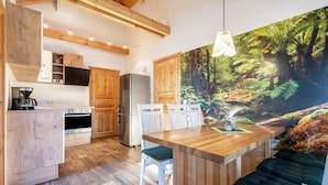 A modern kitchen with wooden cabinetry, a central island, and a dining area with white chairs.