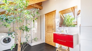 A modern kitchen with a washing machine, a red cabinet, and a wooden door.