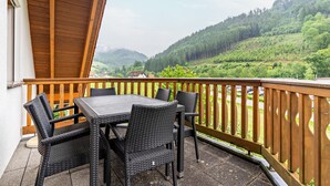 A balcony with a table and chairs, overlooking a green landscape with hills. - Holiday Apartment 'Sum' with Mountain View, Shared Garden, and Wi-Fi (Oberwolfach)