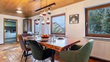 A dining area with a wooden table, chairs, and hanging light fixtures.