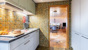 Una cocina con salpicadero de azulejos, una encimera con alimentos y una puerta que da a un comedor.