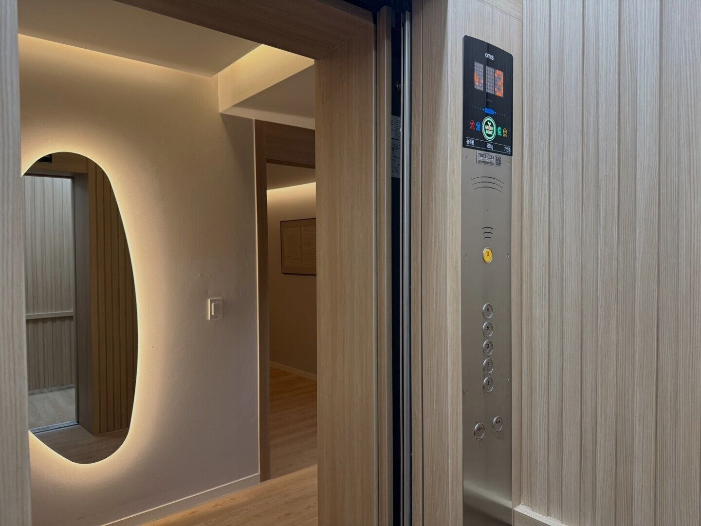 An elevator interior with a digital display, control buttons, and a mirror.