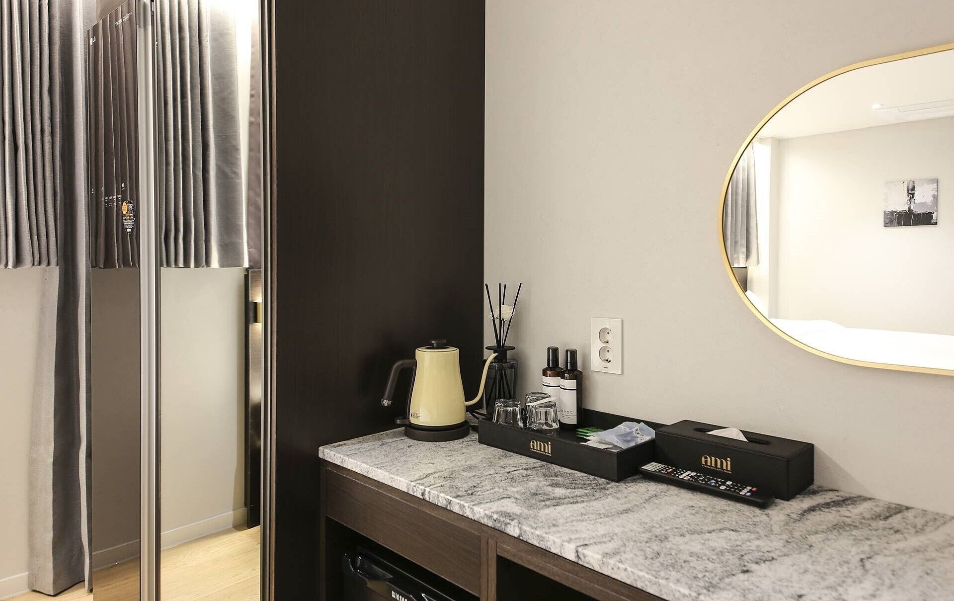 A modern bathroom with a marble countertop, a round mirror, and a dark wall.