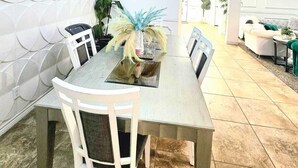 Un comedor con una mesa, sillas, una araña y un cuadro colgado en la pared.