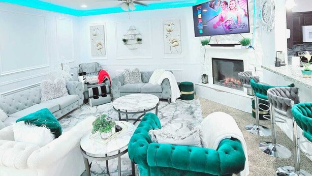 Una sala de estar moderna con un sofá modular, una mesa redonda de centro y un televisor montado en la pared.