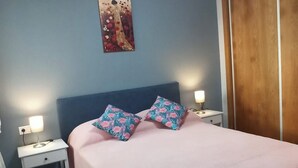 A bedroom with a bed, two nightstands, a wall-mounted painting, and a wooden door. - 2 Bed Apt - Close To Beach - Pool - Balcony (Mojacar)