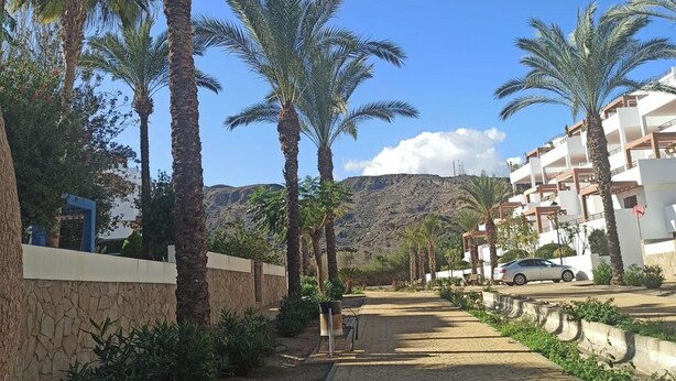 A residential area with palm trees, a paved walkway, and a mountain in the background. - 2 Bed Apt - Close To Beach - Pool - Balcony (Mojacar)