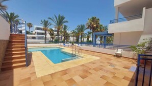 A swimming pool with a tiled deck, a staircase, lounge chairs, and palm trees. - 2 Bed Apt - Close To Beach - Pool - Balcony (Mojacar)