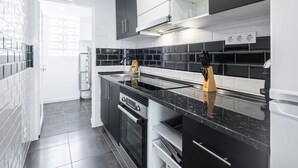 Une cuisine moderne avec des meubles de rangement noirs et blancs, un plan de travail noir et un four encastré.