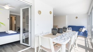Une pièce moderne et bien éclairée, avec une table à manger, des chaises et un canapé bleu.