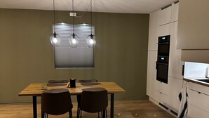 Ett modernt kök med ett matbord i trä, två stolar och hängande lampor.