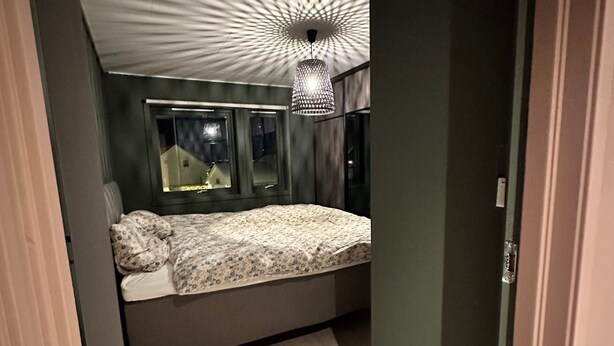 Ett modernt sovrum med en säng, en hängande lampa och ett fönster.