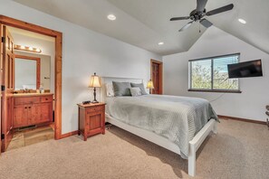 A bedroom with a bed, a nightstand, a mirror, a ceiling fan, and a TV mounted on the wall. - 3-bedroom Cabin 13 in Bridges Bay, with on site eating and in/outdoor pool. (Arnolds Park)