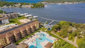 An aerial view of a hotel with a swimming pool, a bridge, and a lake in the background. - 3-bedroom Cabin 13 in Bridges Bay, with on site eating and in/outdoor pool. (Arnolds Park)