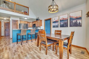 A spacious kitchen with wooden cabinets, a central island with bar stools, and a dining area with a wooden table and chairs.