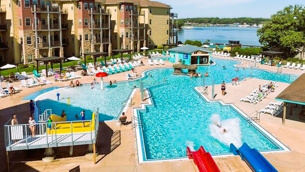 A pool area with multiple swimming pools, lounge chairs, and a water slide.