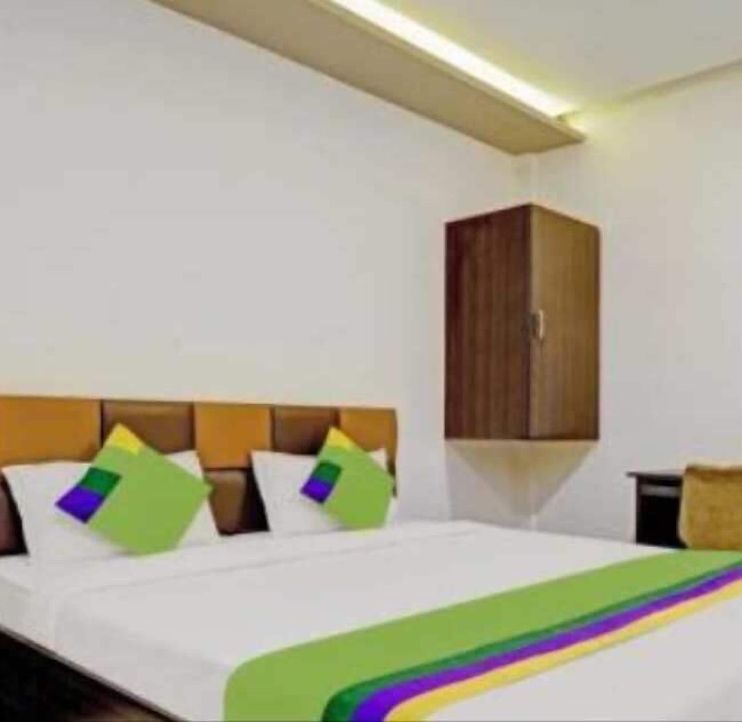 Una habitación de hotel con cama, armario de madera y mesita de noche.