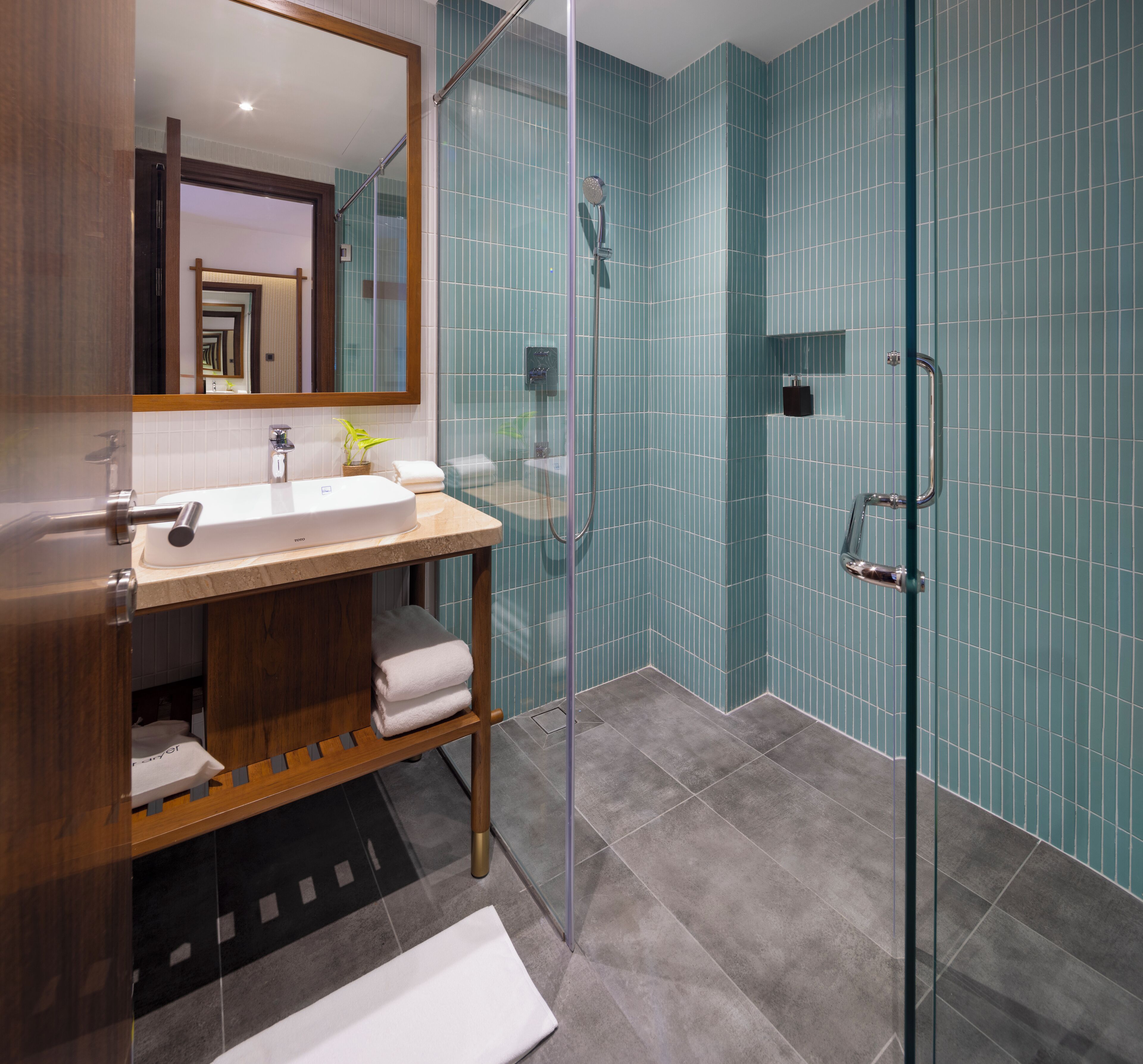 A modern bathroom with a glass-enclosed shower, a wooden vanity with a sink, and a mirror above it.