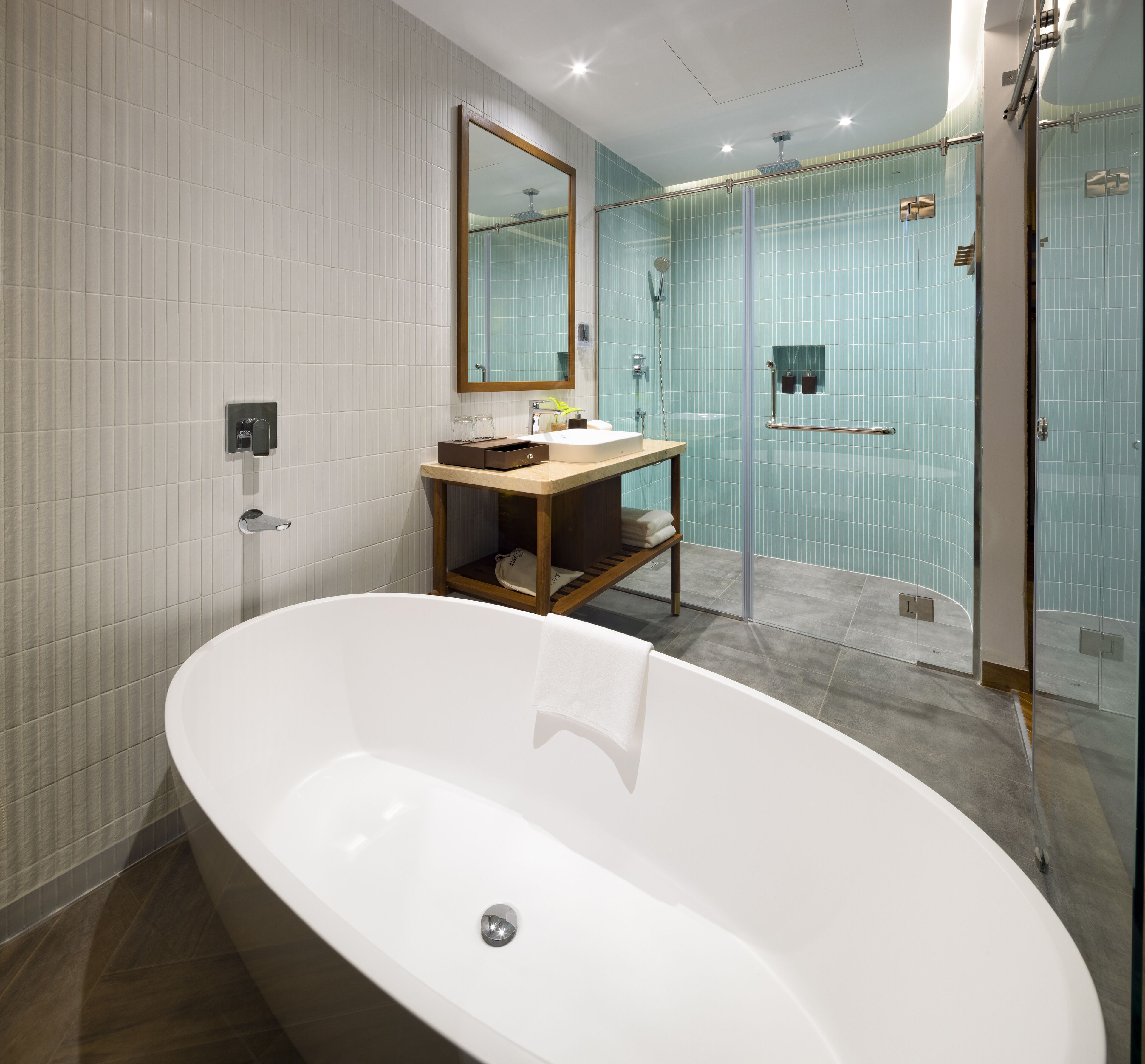 Un baño moderno con una bañera independiente, una ducha con mampara de cristal y un tocador con espejo.