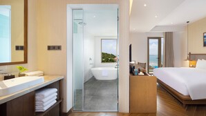 A modern hotel room with a large bed, a bathroom with a bathtub, and a view of the sea. - Iconic Long Hai Hotel (Ho Chi Minh City)