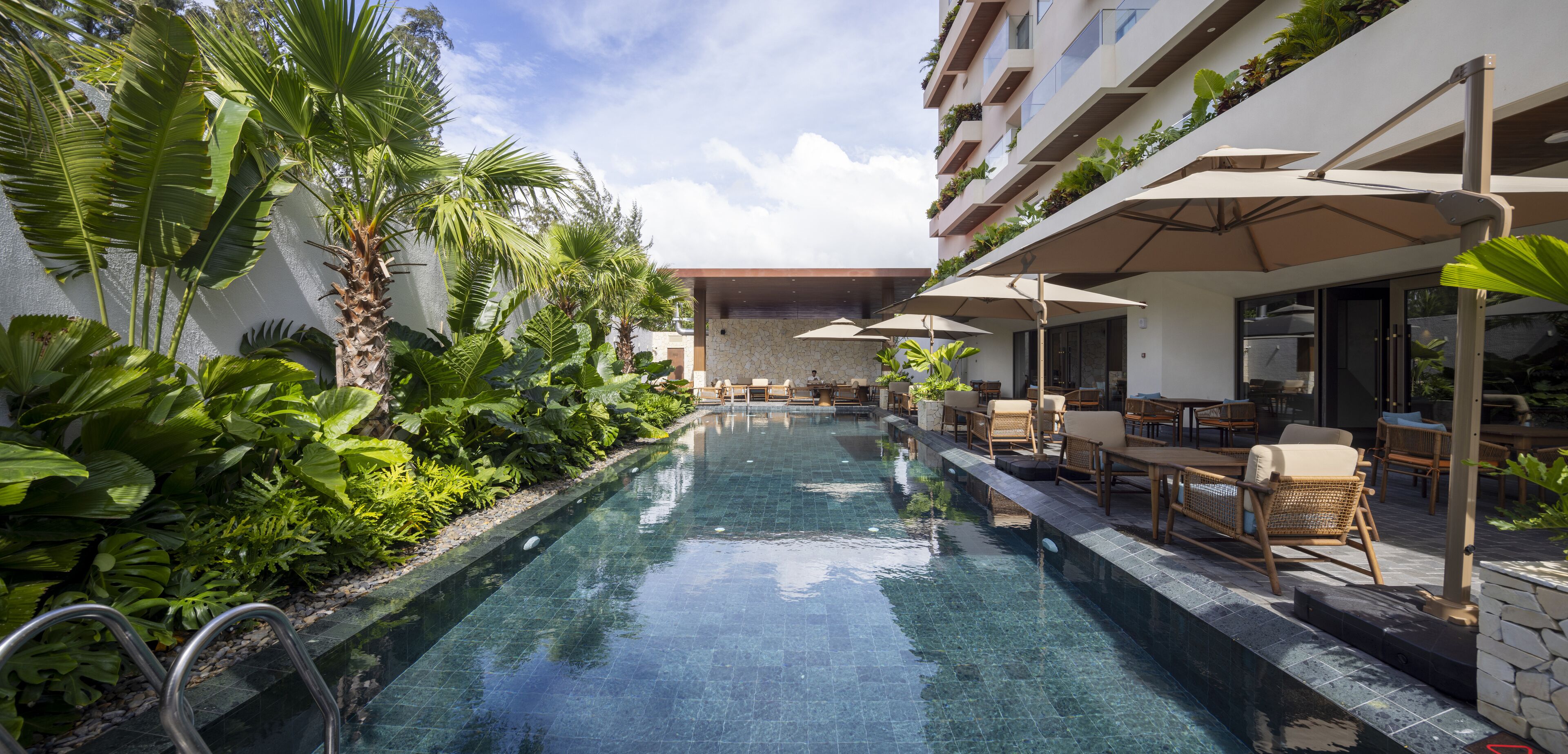 Een buitenzwembad, parasols bij het zwembad en ligstoelen