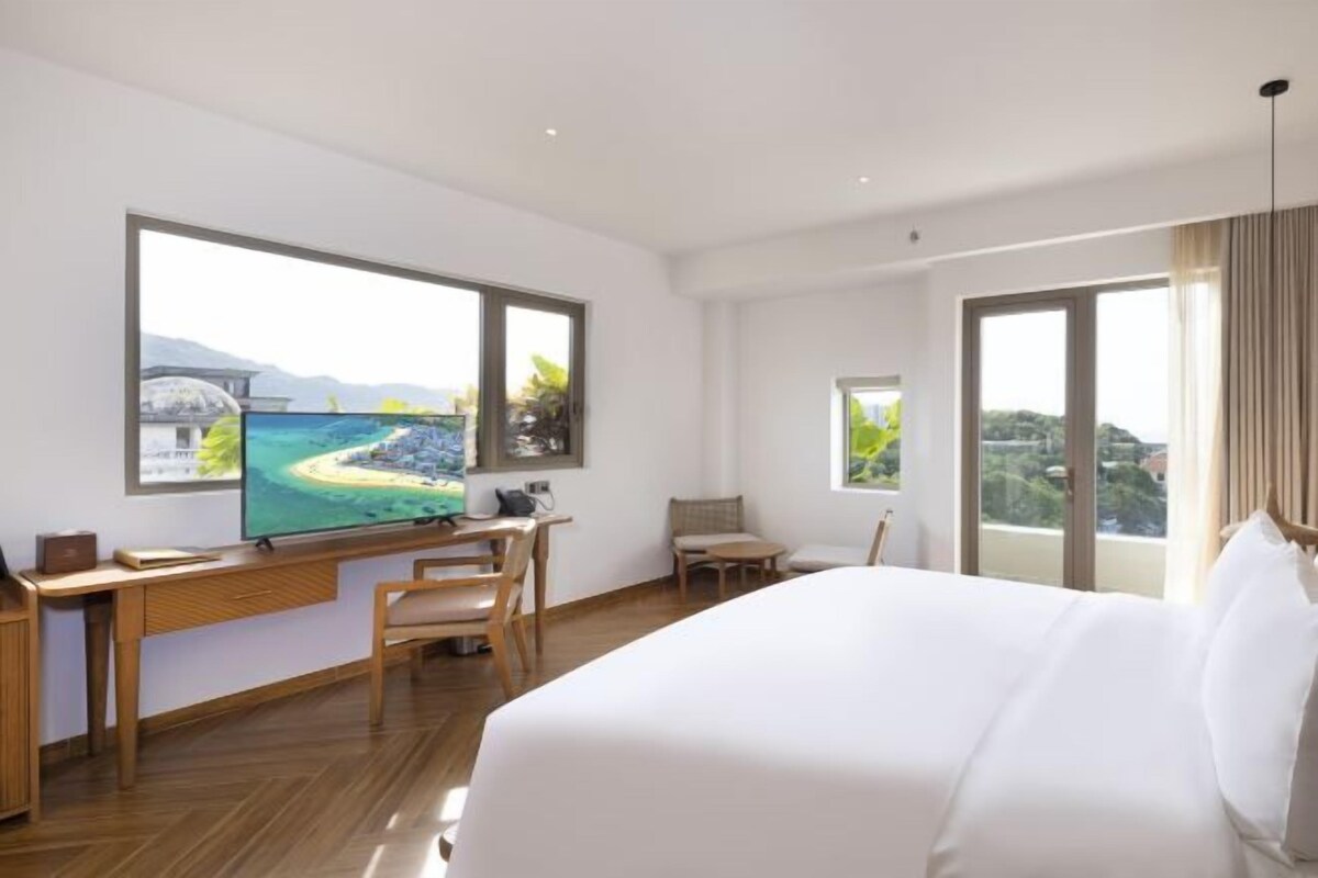 Una habitación de hotel moderna con una cama grande, un escritorio y un televisor que muestra una vista panorámica.