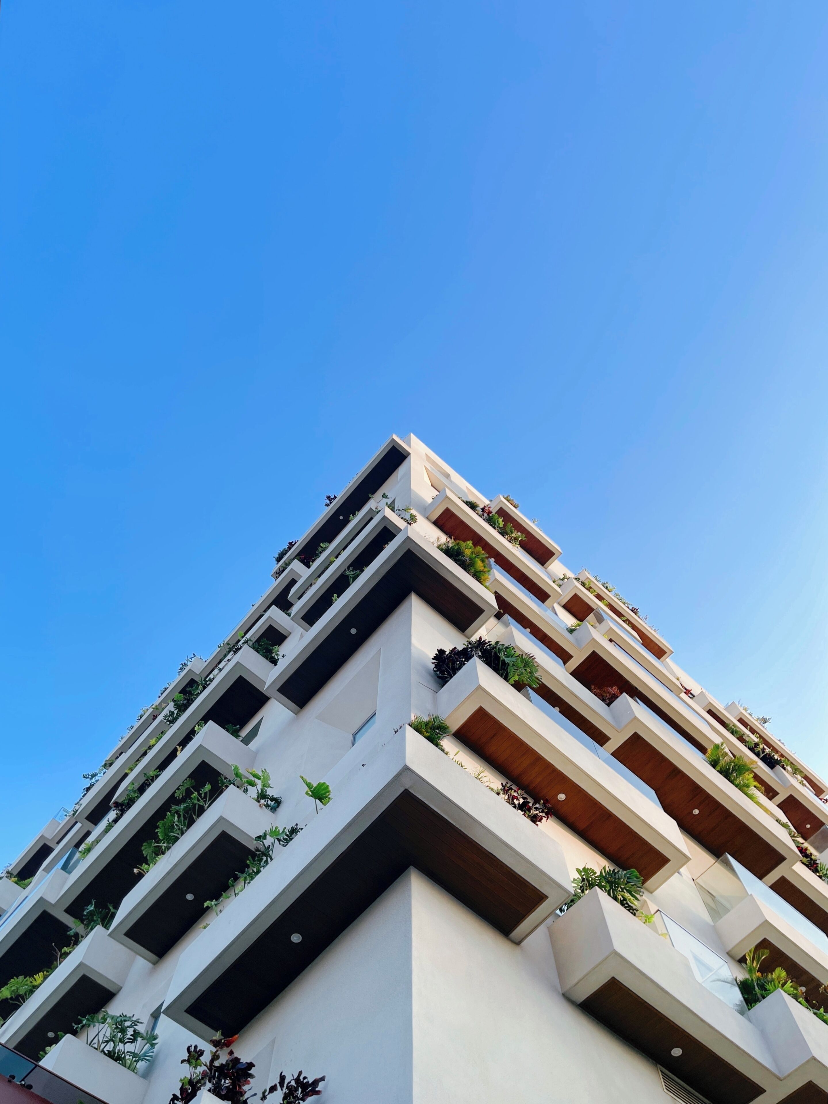 Un immeuble à plusieurs étages doté de balcons, chacun orné de plantes.
