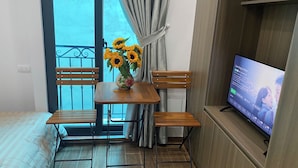 Een kamer met een houten tafel, twee stoelen, een televisie en een raam met gordijnen.