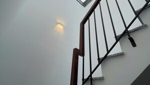 Een trap met een dakraam en een wandlamp.