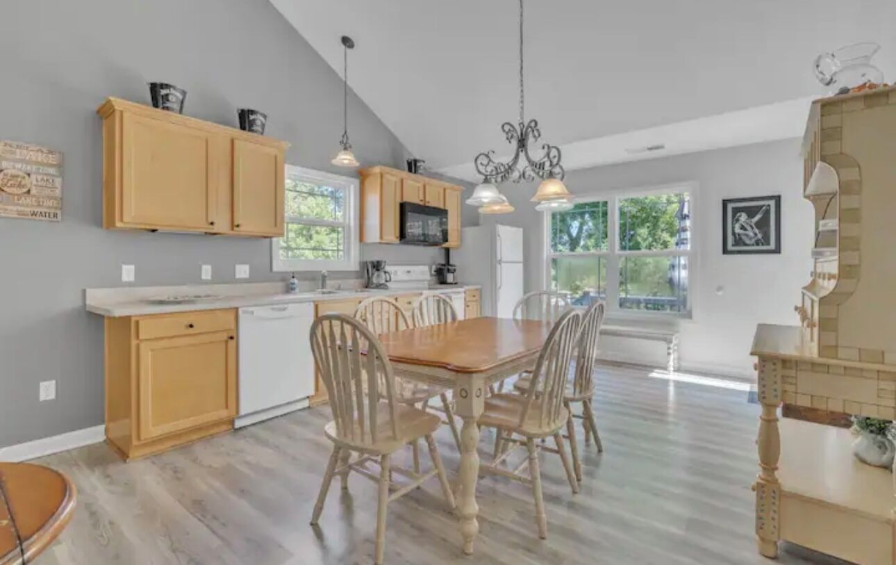A spacious kitchen with wooden cabinets, a dining table with chairs, and a chandelier.