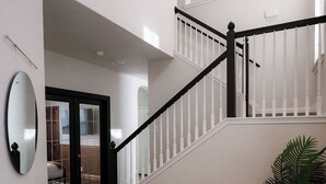 Een trap met witte leuningen en een zwarte handrail, die naar een hoger gelegen niveau leidt.