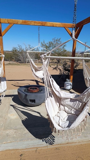 A wooden structure with two hammocks suspended from it, a fire pit, and a gas cylinder. - Welcome to Joshua Tree Getaway – Your Desert Oasis Awaits (Joshua Tree)