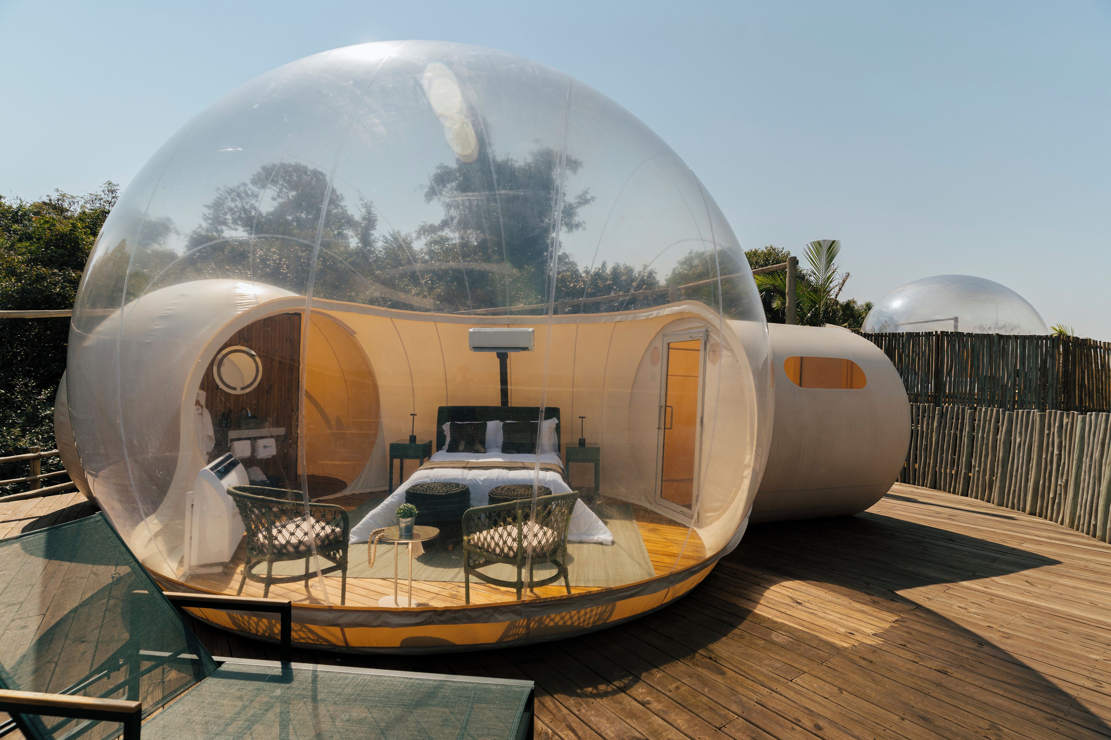 A transparent dome structure with a bed, seating area, and a small table.