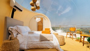 Une pièce circulaire et accueillante, dotée d’un lit, d’un coin salon et offrant une vue sur le paysage.